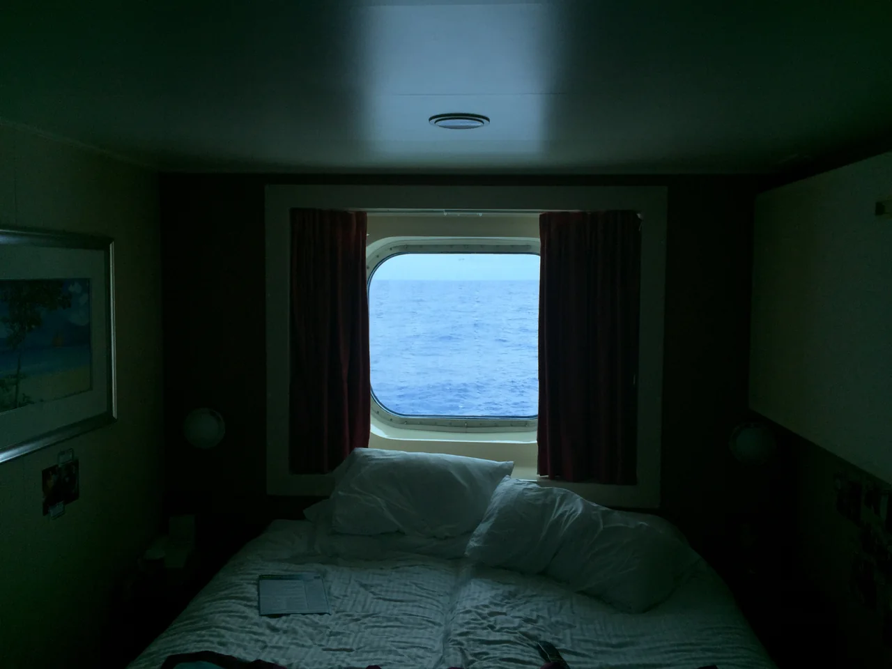 The actual cabin with a bed beneath a large ocean-facing window